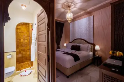 a bedroom with a bed and a bathroom with a tub at Riad Mabrouk in Marrakech