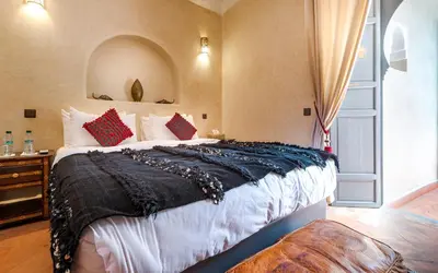 a bedroom with a large bed with red and black pillows at Dar Picolina in Marrakech