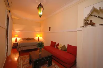 a living room with a red couch and a bed at Riad El Sagaya in Marrakech