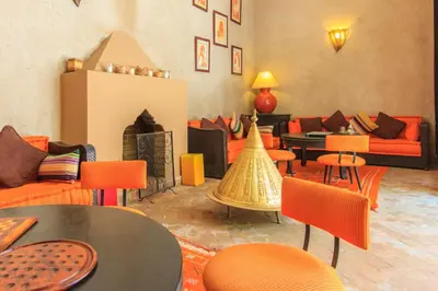 a living room with orange furniture and tables and chairs at Riad Nabila in Marrakech