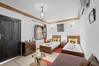 a bedroom with two beds and a door at Riad Marwa Marrakech in Marrakech
