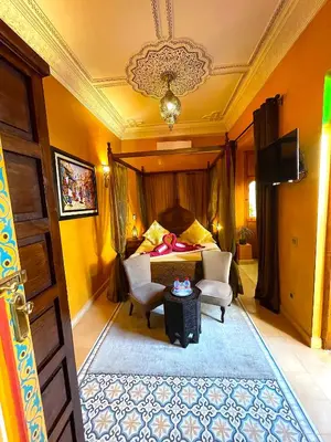 a bedroom with a bed and two chairs and a table at Riad La Perle Rouge in Marrakech