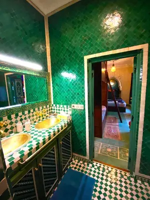a green tiled bathroom with two sinks and a mirror at Riad La Perle Rouge in Marrakech