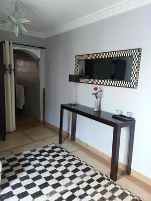 a living room with a table and a mirror at Riad AZZA in Marrakech