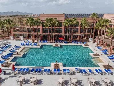 a large swimming pool with blue chairs and palm trees at Pickalbatros Hôtel Du Golf - Adults Friendly 16 Years Plus- All-Inclusive in Marrakech