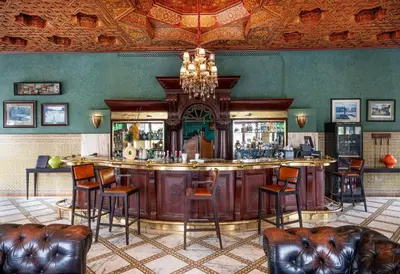 a bar in a restaurant with leather chairs and a chandelier at Pickalbatros Hôtel Du Golf - Adults Friendly 16 Years Plus- All-Inclusive in Marrakech
