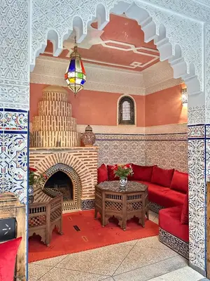 a living room with a red couch and a fireplace at Riad Tasneem in Marrakech