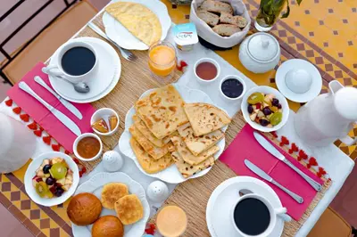 a table with breakfast foods and cups of coffee at Abelia Riad - 2025 Guest Choice Award in Marrakech