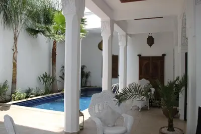 a villa with a swimming pool and white columns at Riad Bellamane Marrakech in Marrakech