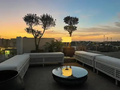 a rooftop patio with white benches and a sunset at Riad Safar in Marrakech