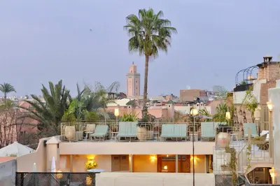 a view of a building with chairs and a palm tree at Riad Anjar in Marrakech