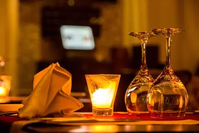 two wine glasses and a candle on a table at Adam Park Marrakech Hotel & Spa in Marrakech