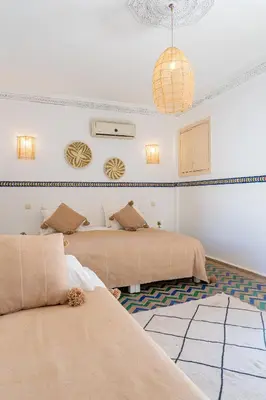 a bedroom with two beds and a rug at Riad Le Marocain in Marrakech