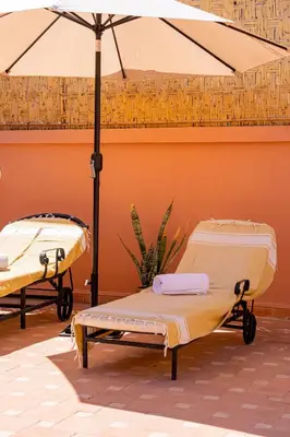 two beds in a room with an umbrella at Riad Le Marocain in Marrakech