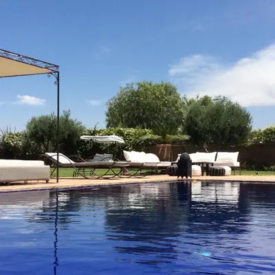 a swimming pool with chairs and an umbrella at Palais Lona in Marrakech