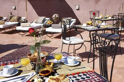 a table with plates of food and drinks and chairs at Riad Shaloma in Marrakech