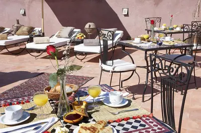 a table with plates of food and drinks and chairs at Riad Shaloma in Marrakech