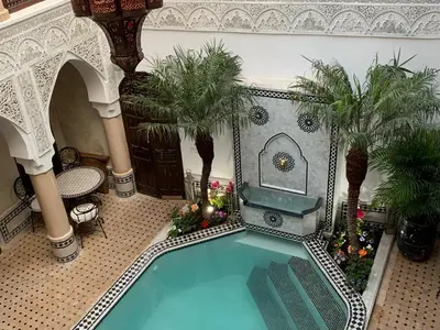 an indoor swimming pool in a building with palm trees at Riad Abaka hotel & boutique in Marrakech