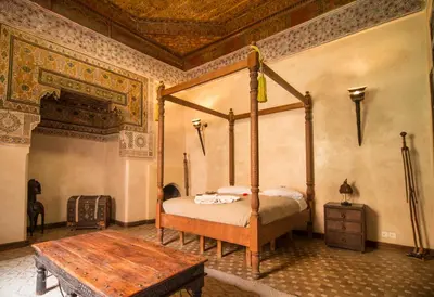a bedroom with a canopy bed and a wooden table at Riad Bamileke in Marrakech