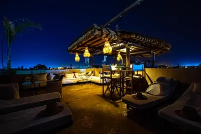 a rooftop patio at night with a table and chairs at Dar Anika in Marrakech