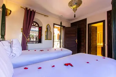 two beds in a room with red roses on them at Dar Anika in Marrakech