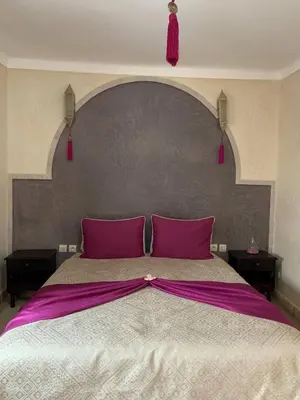a large bed with pink pillows and a large headboard at Riad Karmanda in Marrakech