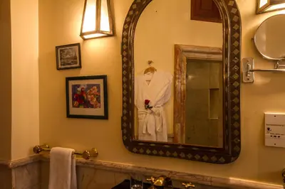 a mirror on the wall of a bathroom with a robe at Palais Dar Donab in Marrakech