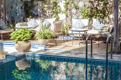 a swimming pool with chairs and a table next to a pool at Riad Palais Sebban in Marrakech
