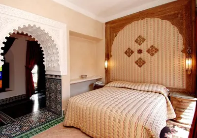a bedroom with a bed and a wall with an arch at Riad Palais Sebban in Marrakech
