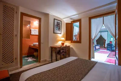 a bedroom with a bed and a desk and a window at Riad l'Heure d'Eté in Marrakech