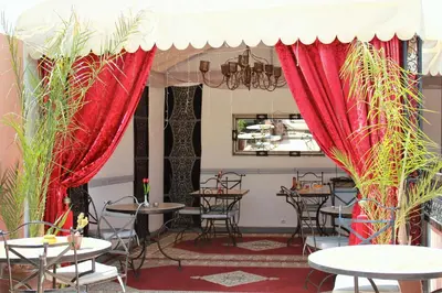 a restaurant with tables and chairs and red drapes at Les Jardins Mandaline in Marrakech