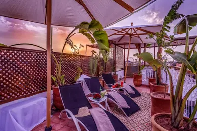 a balcony with chairs and plants and an umbrella at Riad Safran et Cannelle & Spa in Marrakech