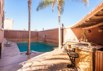 a backyard with a swimming pool and palm trees at Riad Ushuaia - Centre Marrakech in Marrakech