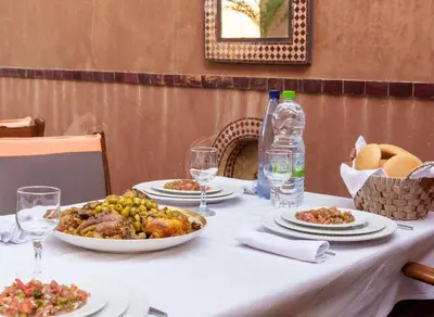 a table with plates of food and a bottle of water at Riad Ushuaia - Centre Marrakech in Marrakech