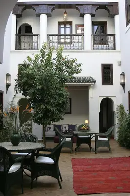 a patio with tables and chairs in front of a building at Riad Chergui in Marrakech