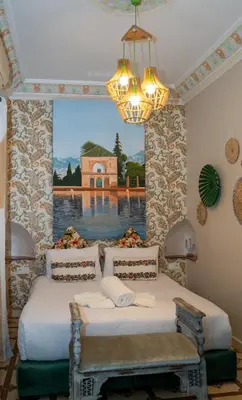 two beds in a room with a painting on the wall at Riad Les Oliviers & Spa in Marrakech