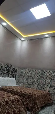 a bedroom with a bed and a wall with a ceiling at Hotel Wissam in Marrakech