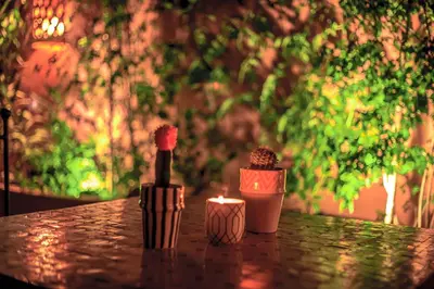 a table with a bottle of wine and a candle at Riad L'orange Bleue in Marrakech