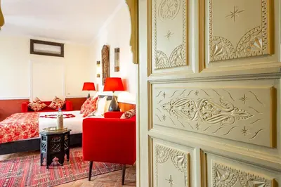 a bedroom with a bed and a red chair at Riad L'orange Bleue in Marrakech