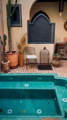 a chair sitting next to a swimming pool with plants at Riad Jonan & Spa in Marrakech