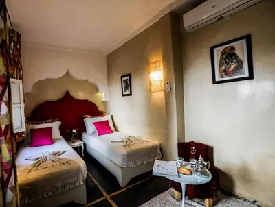 a hotel room with two beds and a table at Riad les 2 Portes in Marrakech