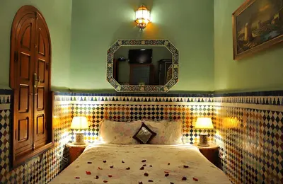 a bedroom with a bed with a mirror on the wall at Riad Lakhdar in Marrakech