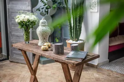 a wooden table with a vase and flowers on it at Riad Dar Tmania in Marrakech