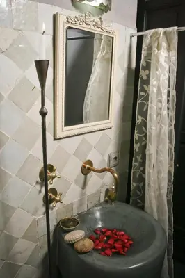 a bathroom with a sink with a candle and a mirror at Riad Golfame in Marrakech