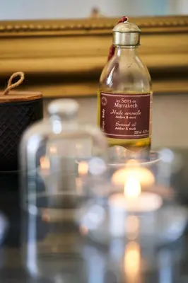 a bottle of oil sitting on a table with a candle at Riad Rafaele & SPA in Marrakech