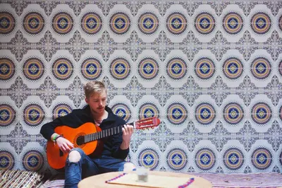 a man sitting on a couch playing a guitar at Mosaic Hostel in Marrakech