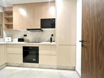a kitchen with wooden cabinets and a black oven at Marrakech golf City prestigia in Marrakech