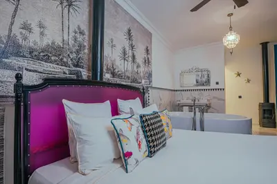 a bedroom with a bed with a purple headboard and a bath tub at Riad Tibibt in Marrakech