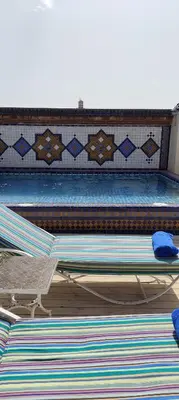 a swimming pool with two beds and a table at Riad Dar Saad - Hammam & Spa in Marrakech