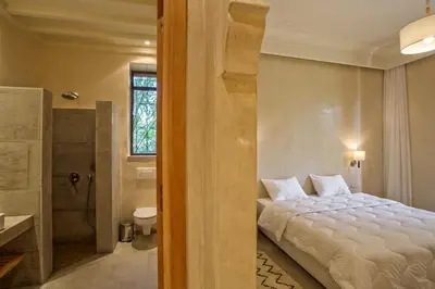 a bedroom with a bed and a bathroom with a shower at Villa Berbère Domaine des Kasbahs in Marrakech